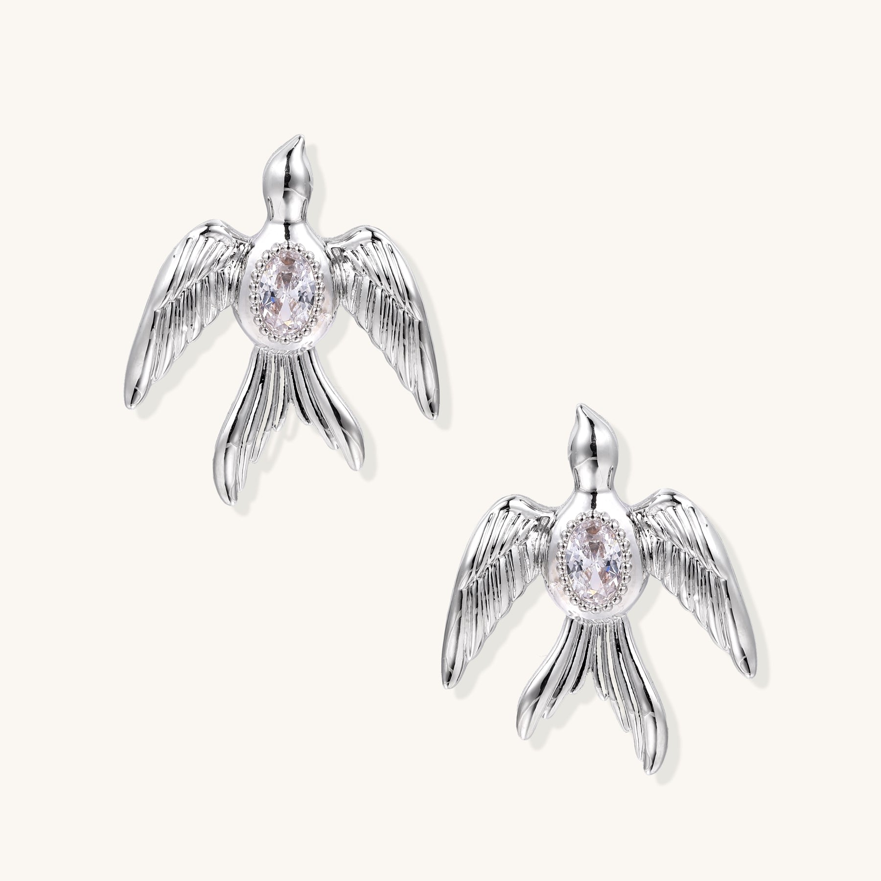 Gold-plated angel wing stud earrings with detailed feather texture and oval zirconia stones in centers
