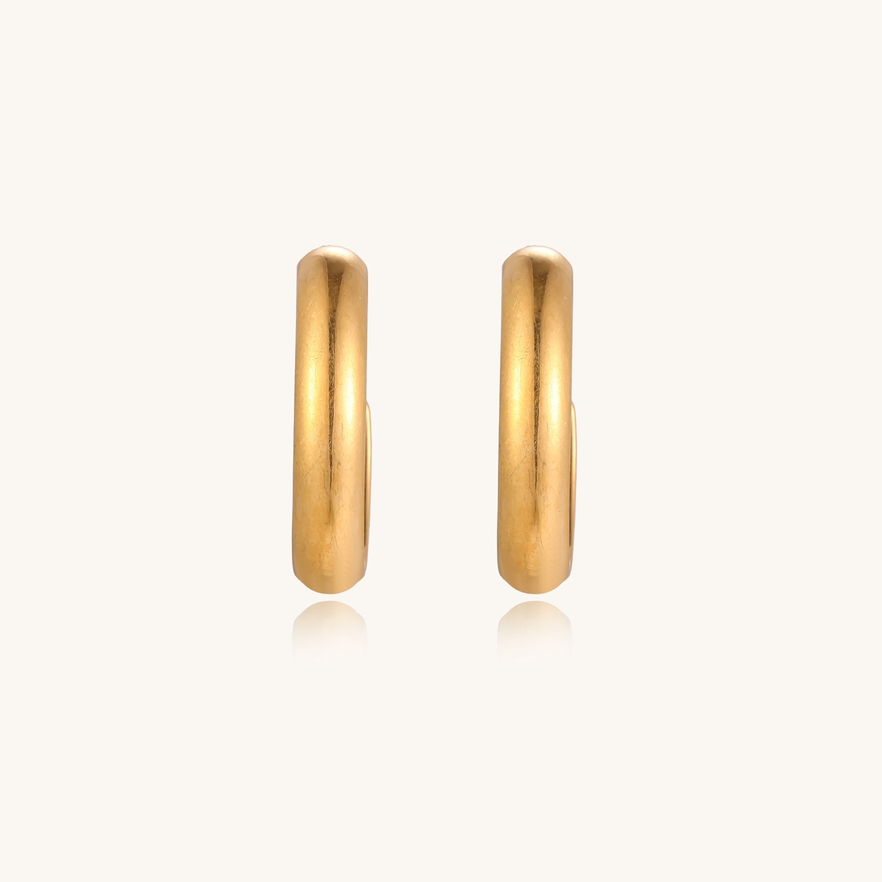 Four pairs of gold-plated stainless steel earrings including hoops and studs displayed on cream background